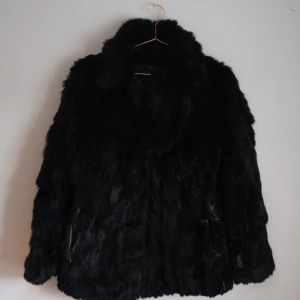  - Äkta svart pälsjacka från Beyond Retro. Små hakar som knäpper igen jackan. Något figursydd och sitter väldigt snyggt men behöver lagas sömmar i fickorna som är öppnade till innerfodret, samt har fläckvis slitningar på undersidan av ärmarna där pälsen lossnat. Syns inte nämnvärt när den sitter på. Möts i Sthlm eller plus frakt.  