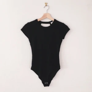  - Svart, kortärmad body från Forever21 med öppen rygg och knappar i grenen. Liten i storleken. 