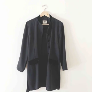  - Svart lätt kavaj med kinakrage och liten axelpuff. Polyester med detaljer i svart sammet. Hel och ren.