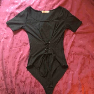  - Svart body i ribbat tyg. Helt ny och oanvänd. Säljes pga fel storlek. 