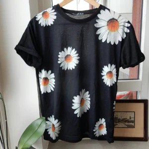  - Blommig t-shirt med ett litet hål på högra ärmen som dock knappt syns. (Se bild 2) Ärmarna var även vikta och fastsydda tidigare men det har jag klippt bort. Går att vika upp eller inte, använd ett fåtal gånger. 