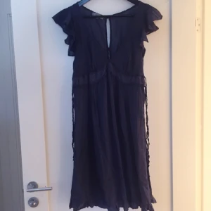  - Sommarklänning i tunt blått tyg. Fina ärmar , knappar bak i ryggen och djup v-ringning