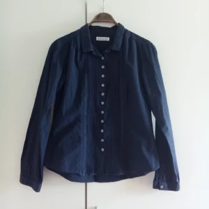  - Mörkblå skjorta från The Shirt Factory. Detaljer som mönstrade knappar och veck fram. 
