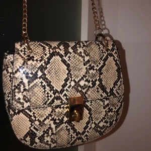 Ormmönstrad handväska  - Skitsnygg och väldigt bra i skick. Ville inte sälja men inte min stil längre..😪 guldiga detaljer och orm mönster med en stor ficka och en liten ficka inuti ✨✨😍