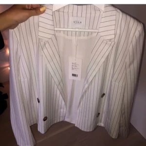 Vit/svart randig blazer - Vit/svart randig blazer från VILA, aldrig använd och prislapp kvar. Eventuell fraktkostnad tillkommer. 