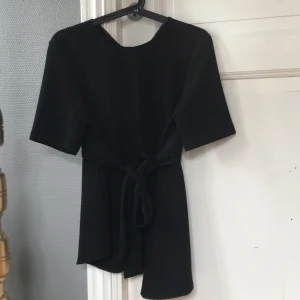 Blus - Svart snedskuren blus från Zara med knyte i midjan, storlek S.