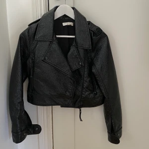 H&M fejkläder jacka - St 38/M - Svart fejkläder jacka som är lite lack inspererad. Passar även xs och s då blir den lite mer overzied. Aldrig använd!