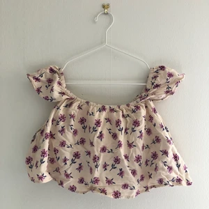 Kort topp/blus med lila blommor  - Toppen är från forever 21, köpt 2014. Använt några gånger, annars ganska bra skick för sin ålder. Tråd som syns på främre sidan. Den är kort i sin längd så passar till högmidjade byxor! 