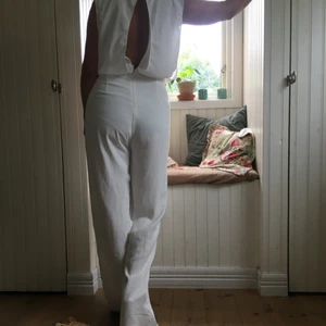  - Vit jumpsuit från märket roser. Öppen fram på bröstet och i ryggen. Utsvängda ben, stängs med en dragkedja i ryggslutet. Använd endast 1 gång.