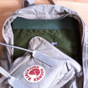  - 💗Beige Kånken, utan namnlapp - med underlag💗

• Storlek: "vanliga"
• Märke: Fjällräven
• Material: -
• Skick: Välanvänd & älskad, gott begagnad
• Övrigt: Bläckfläckar, behöver en tvätt, pin-märken
• Frakt: 45kr