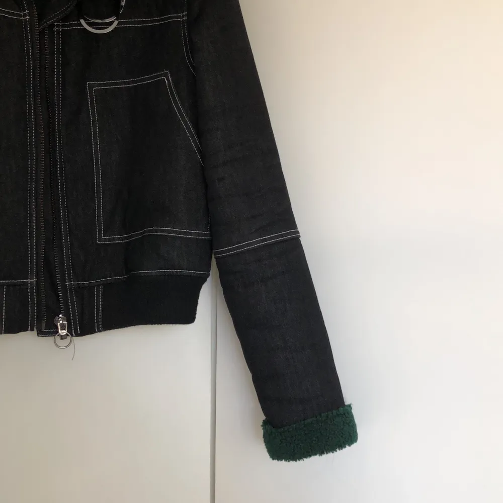 En svart/mörkgrå jacka i jeans material som är fodrar med grönt foder från Urban Outfitters. Har detaljer i vita sömmar och en krage. Knappt använd. . Jackor.