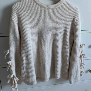  - Beige stickad tröja från zara i xs med rosetter på armarna. Frakt ingår ej.