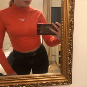 - Croppad tröja med hög krage från Reebok köpt på ASOS. Tröjan är i bomull och passar både till vardags och träning. Reflexmärke i nacken samt logga i fram. Använd endast 1 gång och köpt i höstas så tröjan är i bra skick! (Skriv för fler bilder!)
