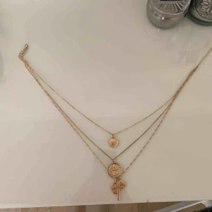  - Guldigt halsband med 3 kedjor med varsin berlock. Aldrig användt, köpt i Australien. Frakt ingår.