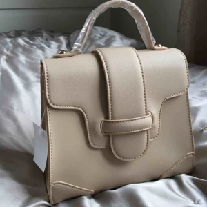  - Väska med bred axelrem samt kort handtag. Aldrig använd. Skinimitation.