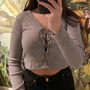 Ribbad topp med snörning - Grå ribbad topp från Bik bok med justerbar snörning och små slitsar på båda sidorna💕 Superfint skick! Priset är inkl. frakt och köparen betalar via Swish✨