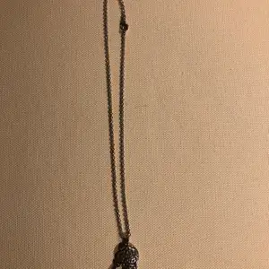 Ett silverfärgat halsband med en liten drömfångare som berlock