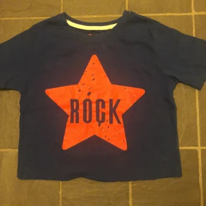 T-shirt - Blå croppad t-shirt med trycket Rock på, i färgerna orang och mörk blå. 