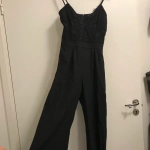 Svart lång jumpsuit med spets - Storlek 36.