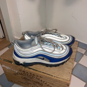 Nike air max 97 - Supersnygga air max 97:or in storlek 38,5 som jag säljer då de inte längre används. Skorna är vita/gråa/blåa. Ränderna på sidan är i reflex villket ger en ascool effekt. Annvända men o fint skick. Frakt tillkommer.