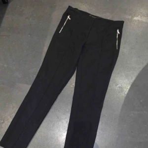  - Ett par svarta kostymbyxor från zara. Storlek 36, har silverkedjor vid fickorna. Har en söm i mitten av byxorna som går hela vägen ner. Köparen står för frakt