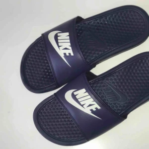  - Ett par marinblå Nike tofflor. Har använts som inneskor, därför inte så slitna. Säljs för 150kr. Betalning sker via swisch :)) köparen står för frakt