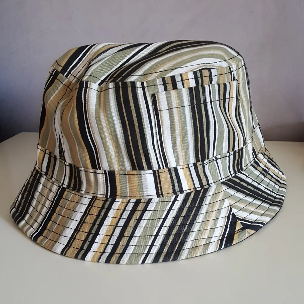 Randig bucket hat i onesize som passar de flesta. Har fickor på sidorna. Fraktkostnaden blir 36kr.. Övrigt.