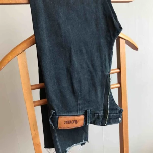  - Avklippta Jeans från Acne i storlek 26/32 Hål över knäna och dragkedja baktill