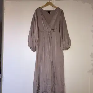 Fin klänning i silkestyg från H&M med halvlång ”puffärm”. Strl 34. Färgen är ljust gammelrosa