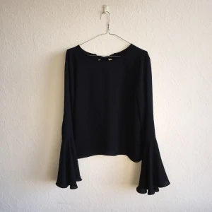  - Svart topp med vida ärmar och djup öppen rygg med knytband från Zara. Sparsamt använd och i fint skick! Materialet är polyester (lapparna är bortklippta eftersom man såg dom). Frakt ingår i priset. 