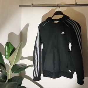  - Svart adidas hoodie med dragkedja och gråa streck. Äldre loggan av adidas :) samt jättefin och välvårdad!