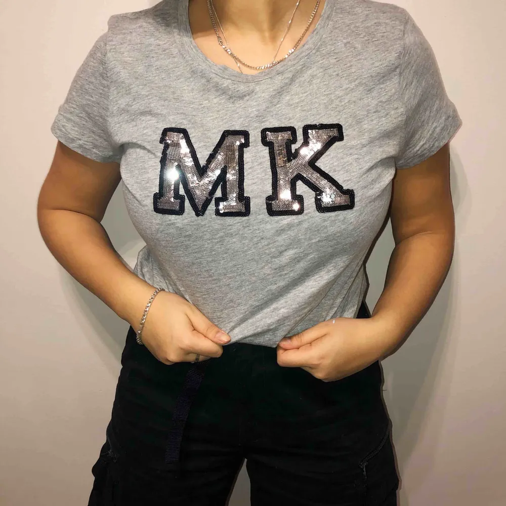 Snygg grå Michael Kors t-shirt med paljetter. Oanvänd, endast testad på bilden. Storlek L men passar en storlek M bättre. Köpt för 1000 kr.. T-shirts.