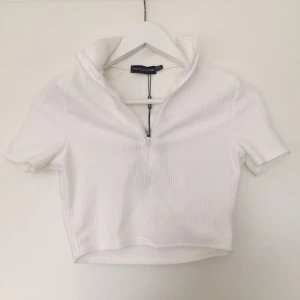 Prettylittlething zip croptop - En så fin å fräsch vit croptop med dragkedja och polokrage från prettylittlething. Helt ny med alla tags kvar 💕 Storlek 36.