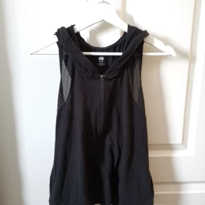 Träningslinne med huva  - Svart linne med huva och meshdetaljer 