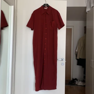 Mörkröd långklänning - Mörkröd långklänning med knäppning och skjortkrage, secondhand men fint skick! Väldigt skön till sommaren. Storlek L men passar även mig som är M om man gillar lite oversize! 