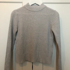 HM - Härlig stickad tröja ifrån HM. Tröjan är något kortare en vanligt. Tröjan är i fint skick. Köparen står för frakten.