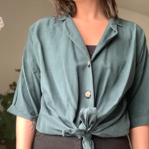Blus med knappar och knytning  - blå/grön blus. Knappt använd 