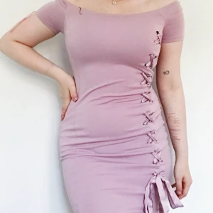 Lace up detail klänning - Rosa bodycon klänning med lace up detalj på hela sidan. Köpt på New Yorker och sparsamt använd. Storlek 34. Kan mötas upp i Sthlm eller skicka frakt ej inkl i priset.
