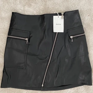 Ny kjol  - Ny svart läderkjol i strl M, lite liten i storleken så passar även S. Köpt på Behrska i Dubai för cirka 300kr. Kan mötas upp i Västerås annars står köparen för frakt.