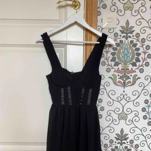  - Svart klänning, slutar ovanför knäna. 