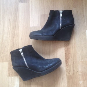  - Svarta kilklackar från Vagabond. Med silvrig dragkedja på utsidan av skorna & en svart på insidan. Tror det är äkta mocka i skorna, men är inte säker. Säljes pga jag använder dem inte längre, men dem är fortfarande i mycket gott skick! Klackhöjd är 9 cm. 