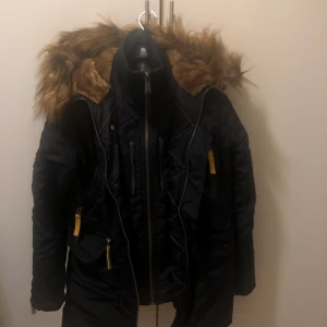 Vinterjacka alpha industries - Hej! Jag säljer min vinterjacka alpha industries som jag har använd få gånger. Den är i färgen mörkblå och är i väldigt bra skick. Den är dock lite missfärgad inuti som ni ser på den sista bilden. Helt äkta, jackan har den röda banden som hänger på armen som dock ej syns på bild. Kan skicka bild om det önskas!Orginal priset för jackan är ca 3000kr. Storlek på jackan är small. Köparen står för frakt! Kontakta mig för mer info/bilder. GÅR ÄVEN BRA ATT BYTA MOT EN PRODUKT/VARA. 