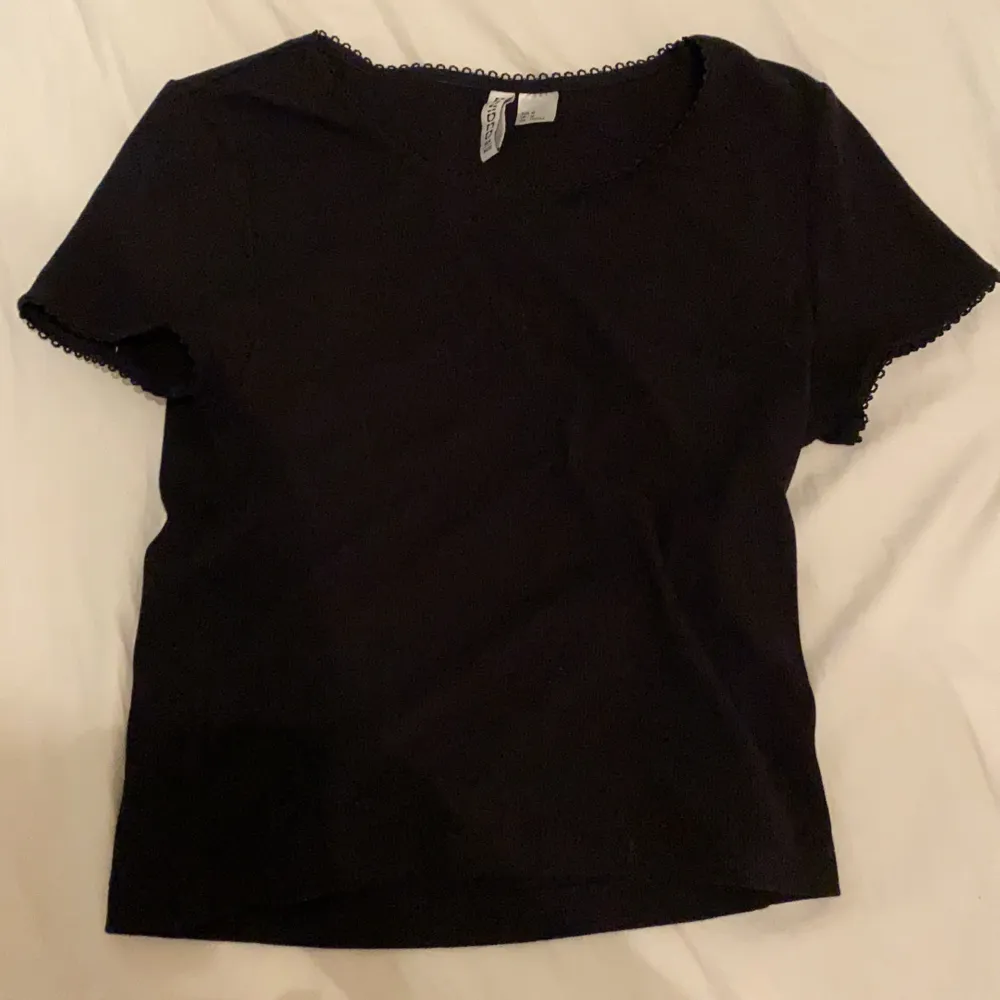 En svart croppad t-shirt med lite volanger på armarna och vid halsen. Lite tajt på armarna . T-shirts.