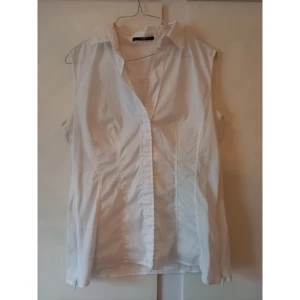 Hugo Boss Under shirt/Blouse - En fin vit skjorta/blus från Hugo Boss. Det öppnad med dragkedjor i båda sidorna och tyget är något stretching men lite genomskinlig, därav min gissning att det är en under shirt i "dammodell". Något skrynklig med annars i gott skick! Priset är prutbart, men inga skambud!