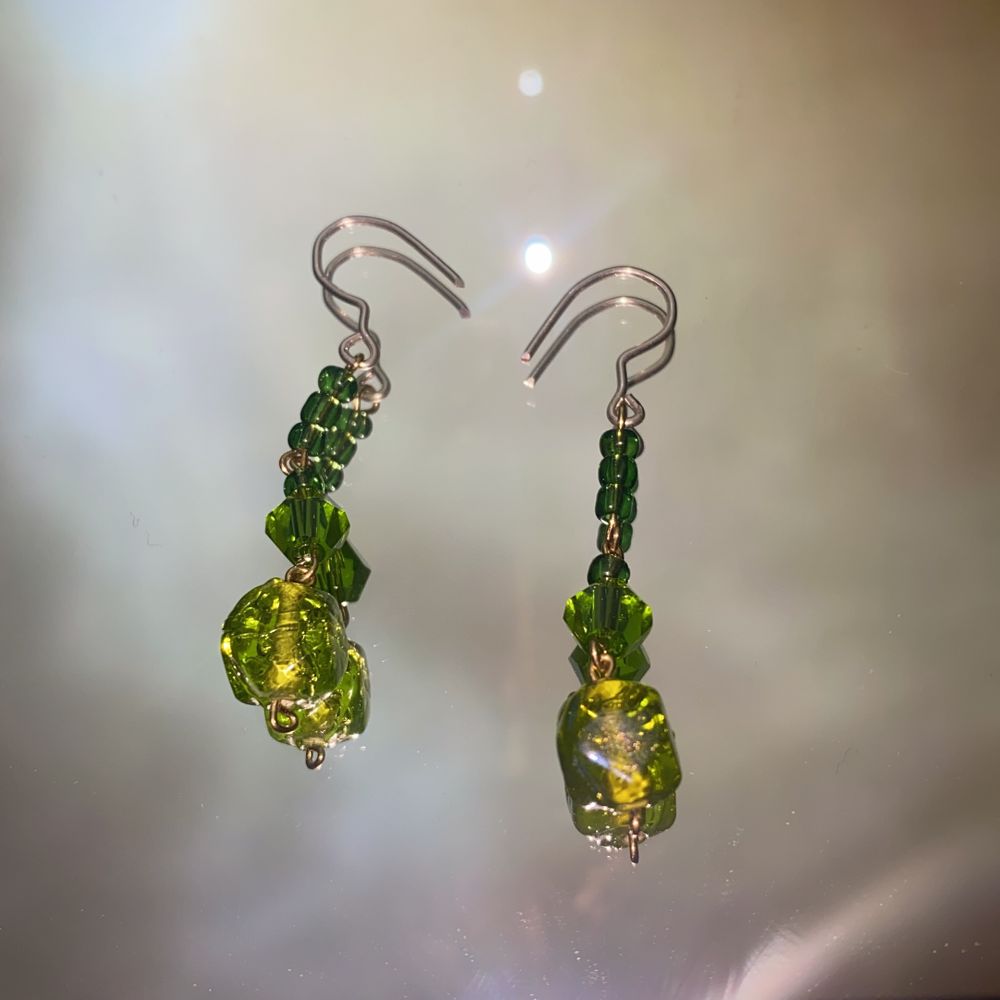 Ett par handgjorda örhängen av metall och gröna glaspärlor✨ kroken är av silvertråd💃🏼 frakten ingår i priset💃🏼. Övrigt.