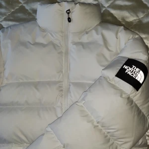 The North Face Nuptse - The North Face Nuptse jacka i färgen vit. Den är helt ny med tags och passar perfekt inför den kalla vintern! Jackan är i herrmodell men sitter minst lika bra om inte bättre på damer!                                           Storlek XS men passar även bra om man har storlek S/M.                                       Slutsålda överallt! Kontakta för fler frågor och skambud ignoreras! SÅLD!