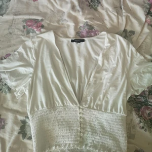 Vit topp i M - Superskön vit topp med resår och knappar nertill och lösa ärmar. Köpt från Forever 21, använd nån gång. Passar inte min stil längre. Är villig att diskutera pris, köpare betalar frakt. 