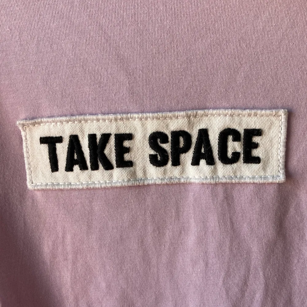 Lila topp med kort polokrage från Monki. Patch framtill ”take space”. . Toppar.