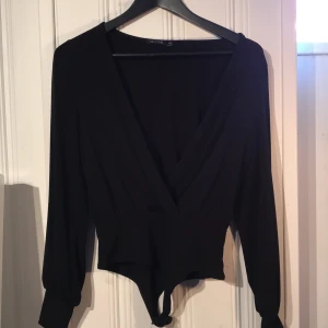 Svart body - Snygg svart v-ringad body med öppna ärmar. Från Nelly och deras märke NLY ONE. Använd en gång. 80kr + frakt