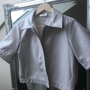 Lacktopp - En supersnygg topp/kortärmad jacka i lackimitation. Köpt i på Monki i London för 350 kr, prislapp kvar. Så häftig men har inte fått användning för den tyvärr. Frakt tillkommer💕